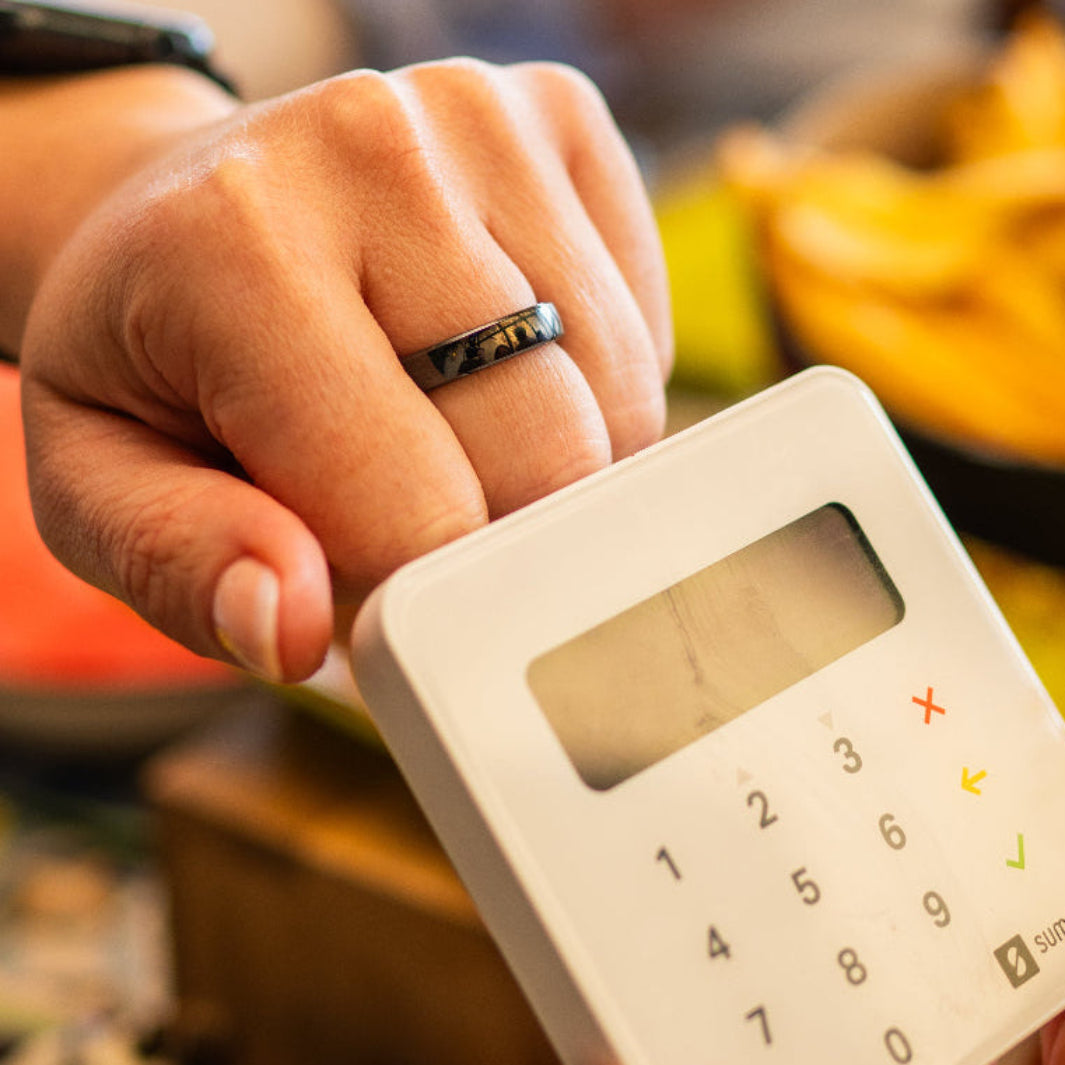 A close up of a woman using RingPay's Zirconia Ceramic Payment Ring to make a contactless payment.