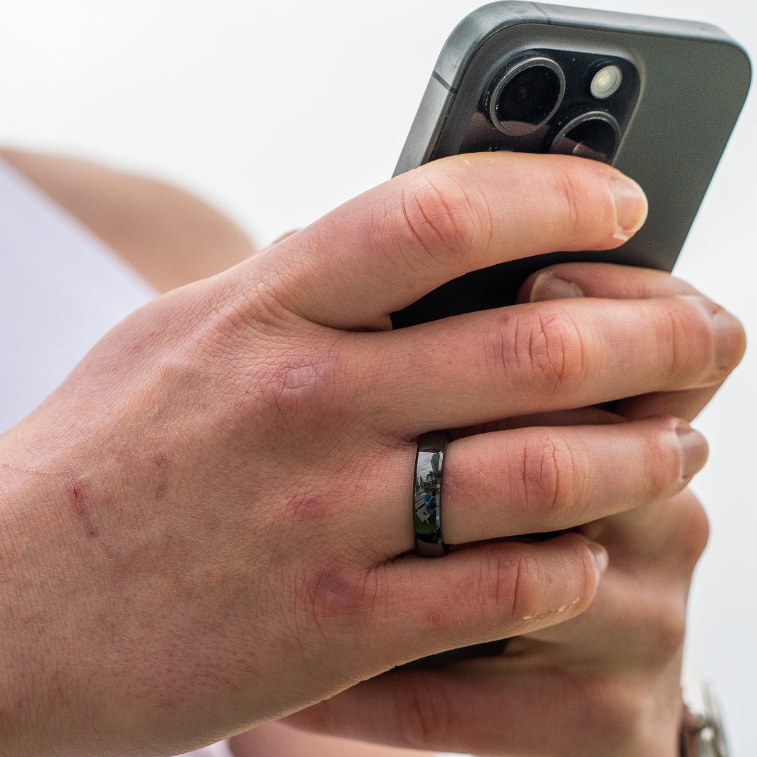 A close up of a person holding their phone while wearing RingPay's Zirconia Ceramic Payment Ring.