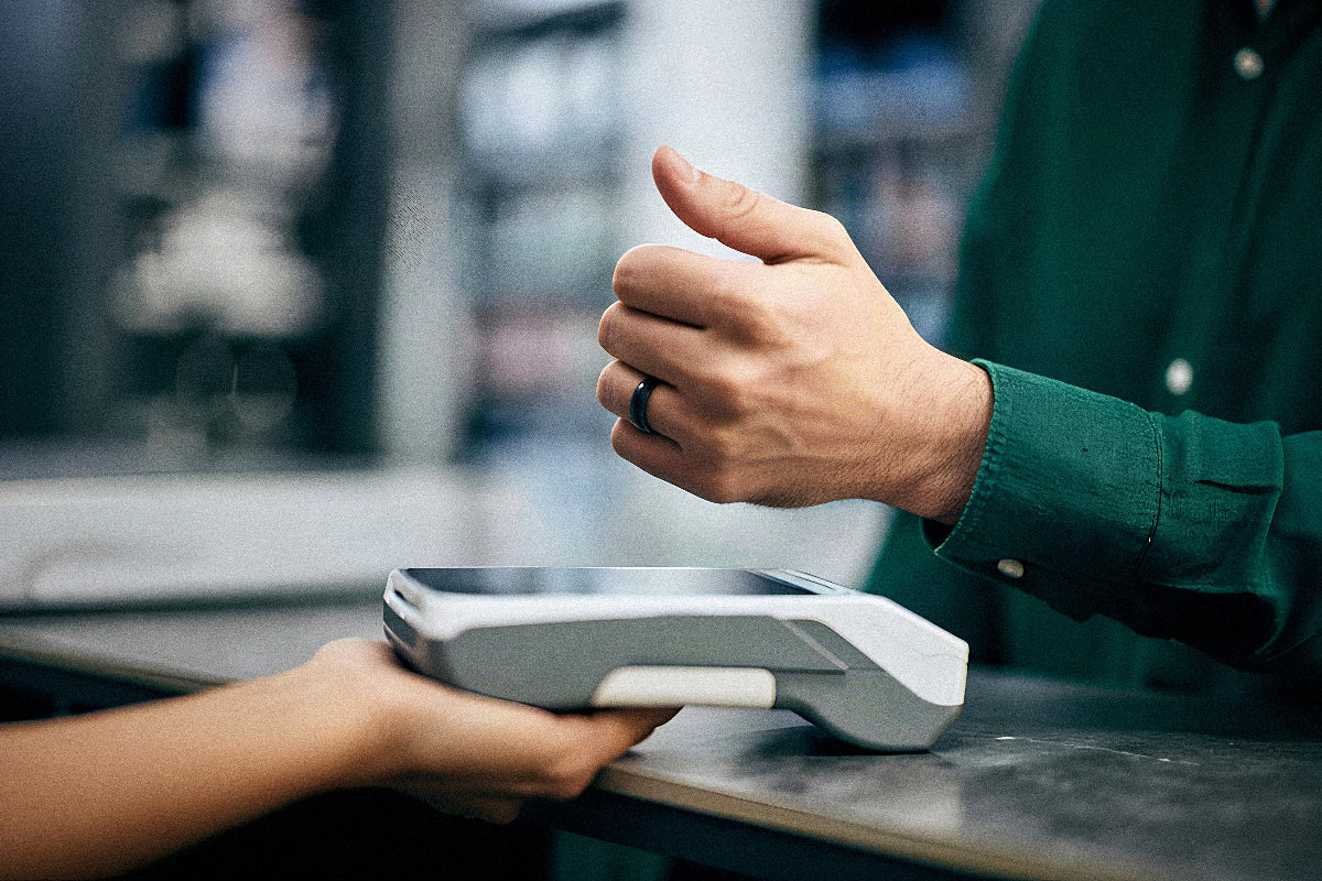 A close up of a man wearing the Zirconia Ceramic Payment Ring tapping on a contactless terminal to pay.